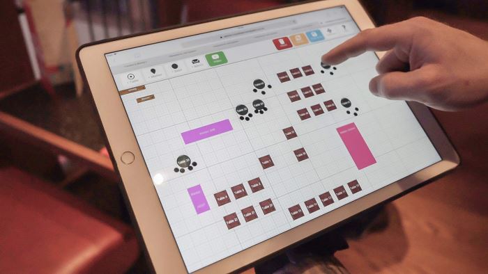 Technician creating a floor plan of a restaurant on a tablet