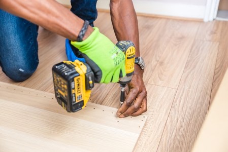 Furniture technician assembling flatpack furniture with an electric screwdriver