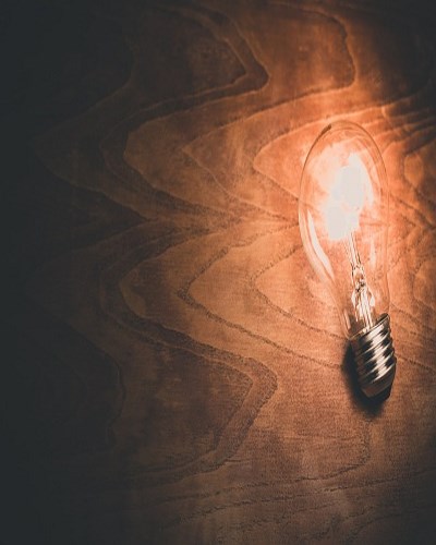 Glowing light bulb on wooden surface